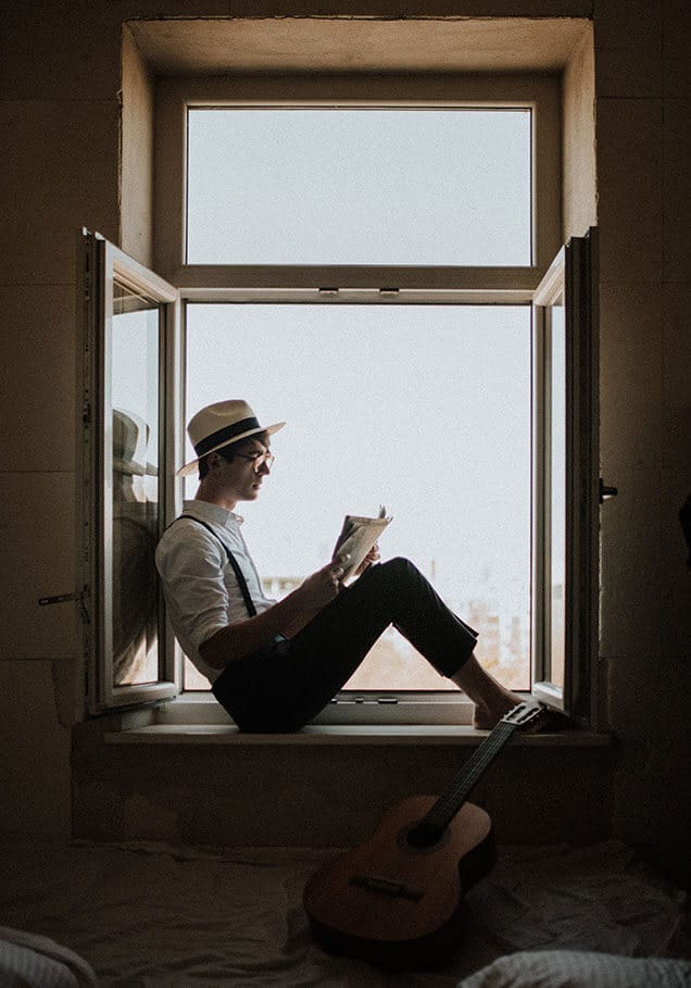 homme lisant livre au bord de la fenêtre